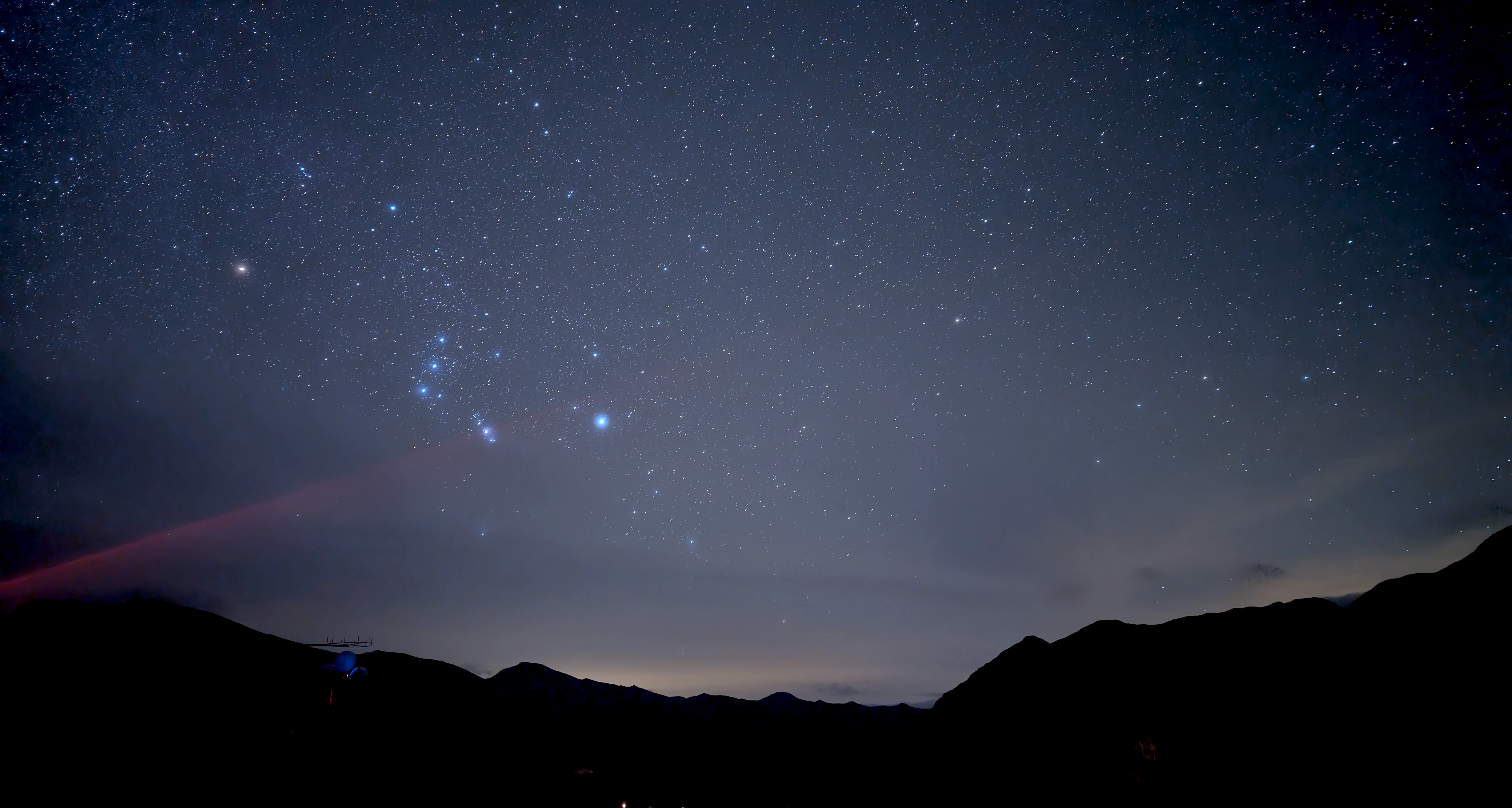 Klarer Nachthimmel mit dem markanten Wintersternbild Orion über dunklen Bergkonturen des Großglockners